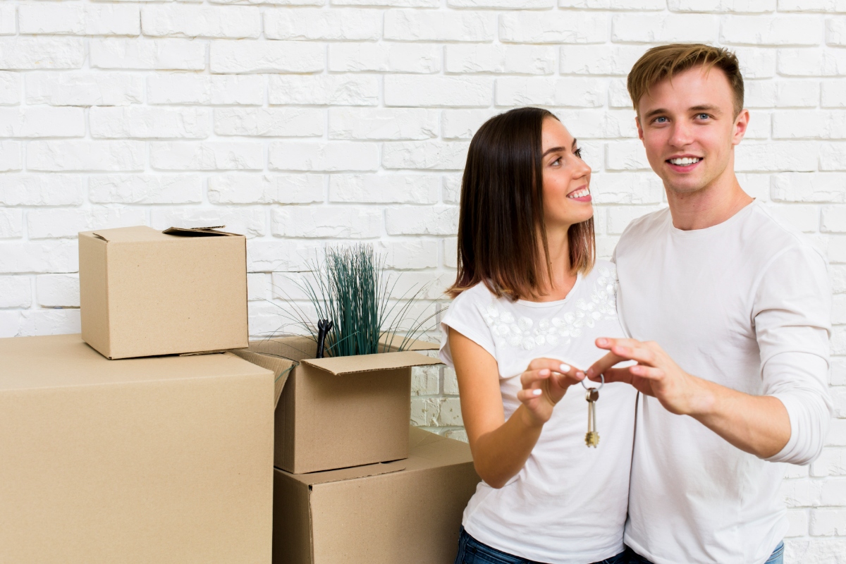 couple holding key with packing boxes in background